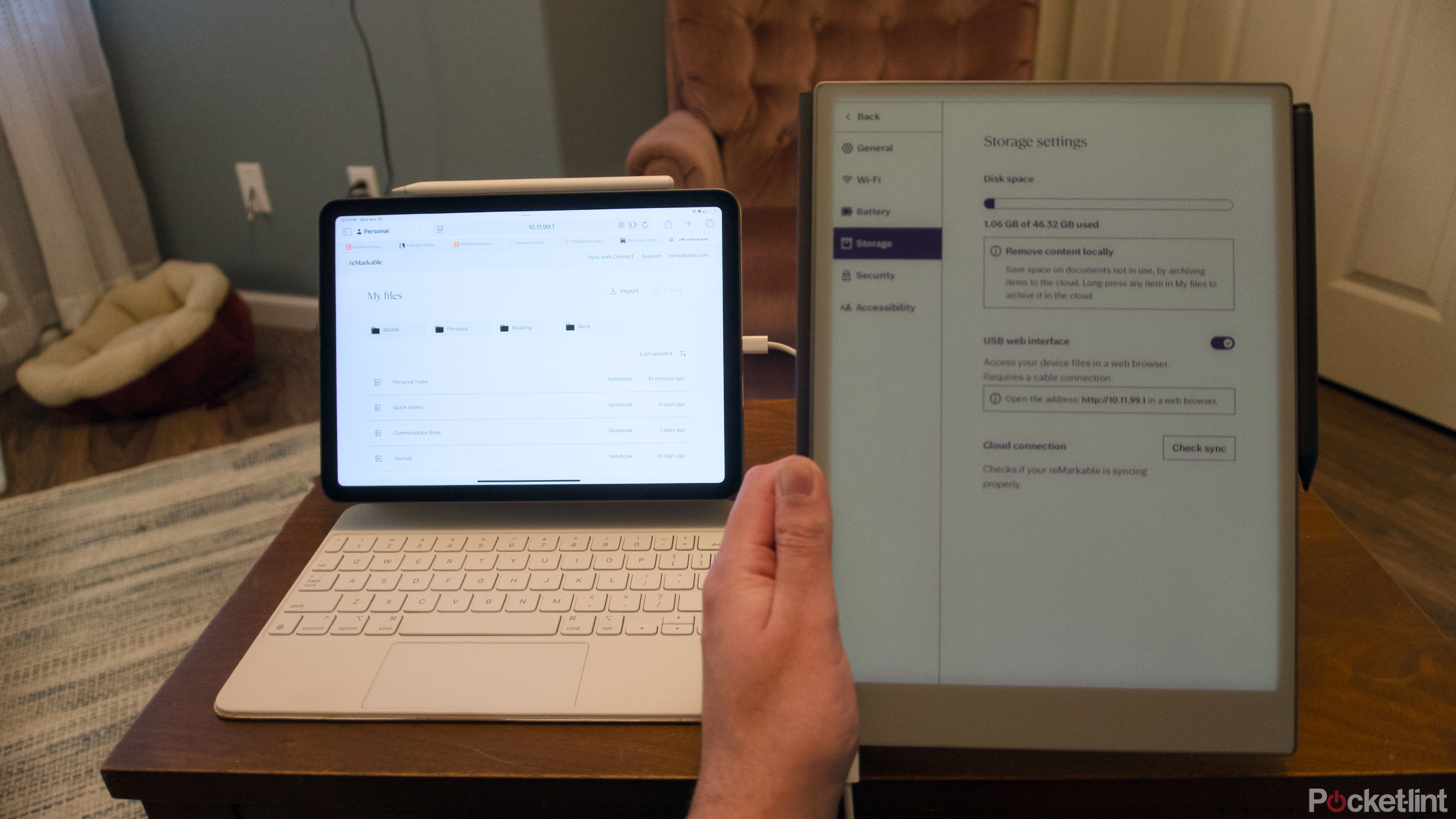 A hand holding a reMarkable Paper Pro next to an iPad Air in a keyboard case.