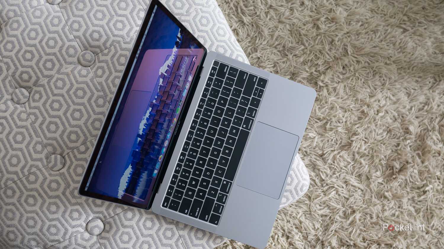 A MacBook Air with a butterfly keyboard sitting on a pillow.