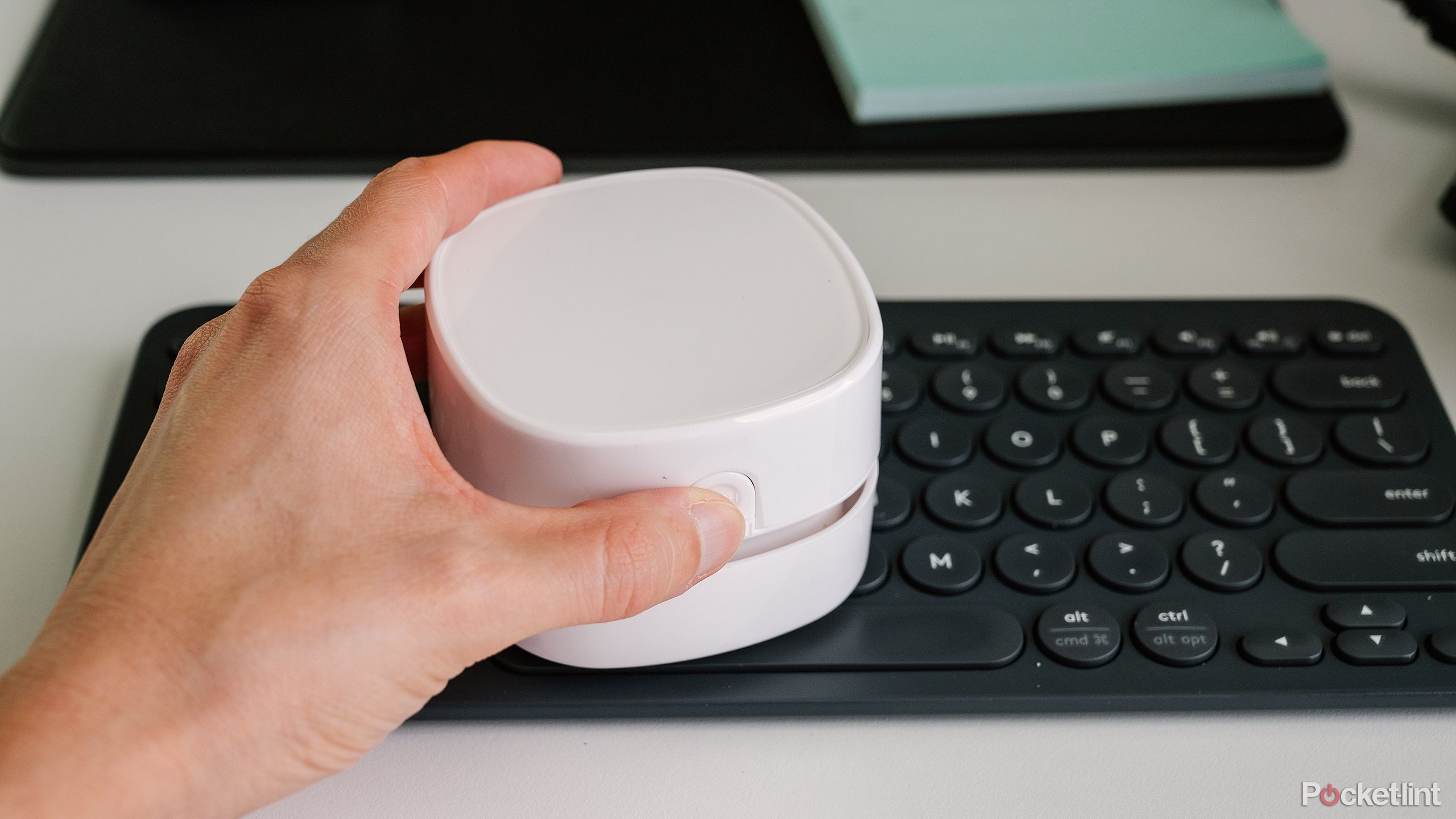 A hand holds the Odistar Desktop Vacuum Cleaner over a keyboard.