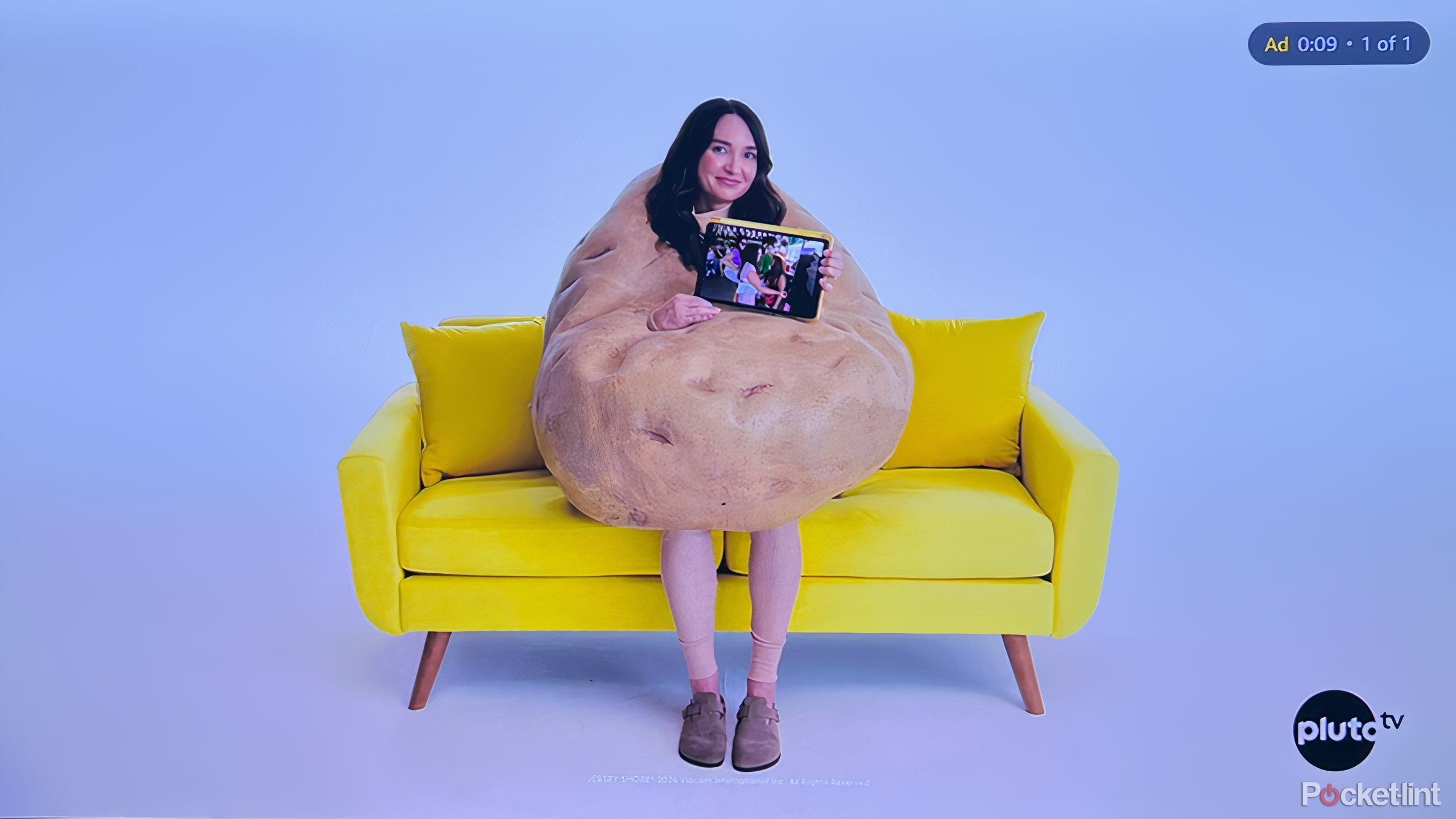 A person sitting on a couch in a potato costume. 