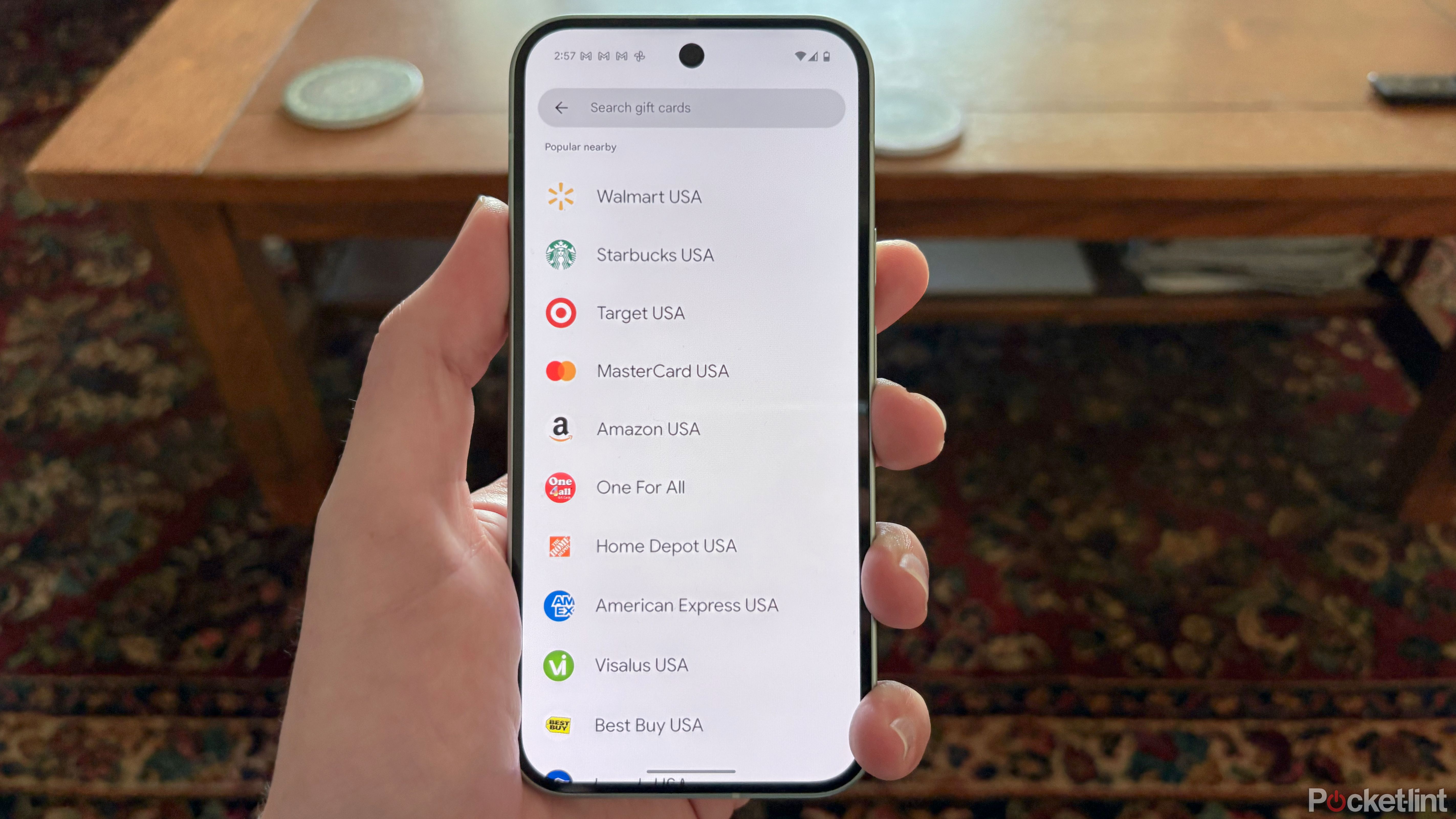 Một tay cầm Pixel 9 hiển thị menu thẻ quà tặng trên ví Google.