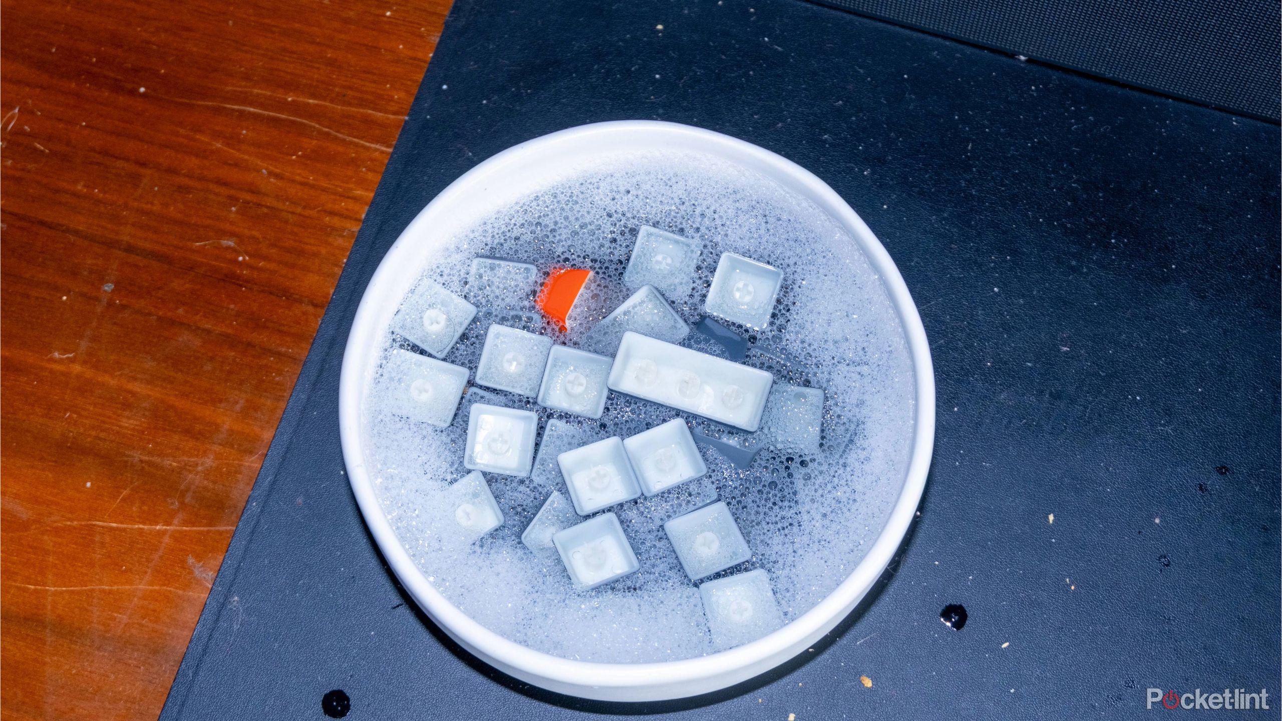 Keycaps soaking in a bowl of dish detergent. 