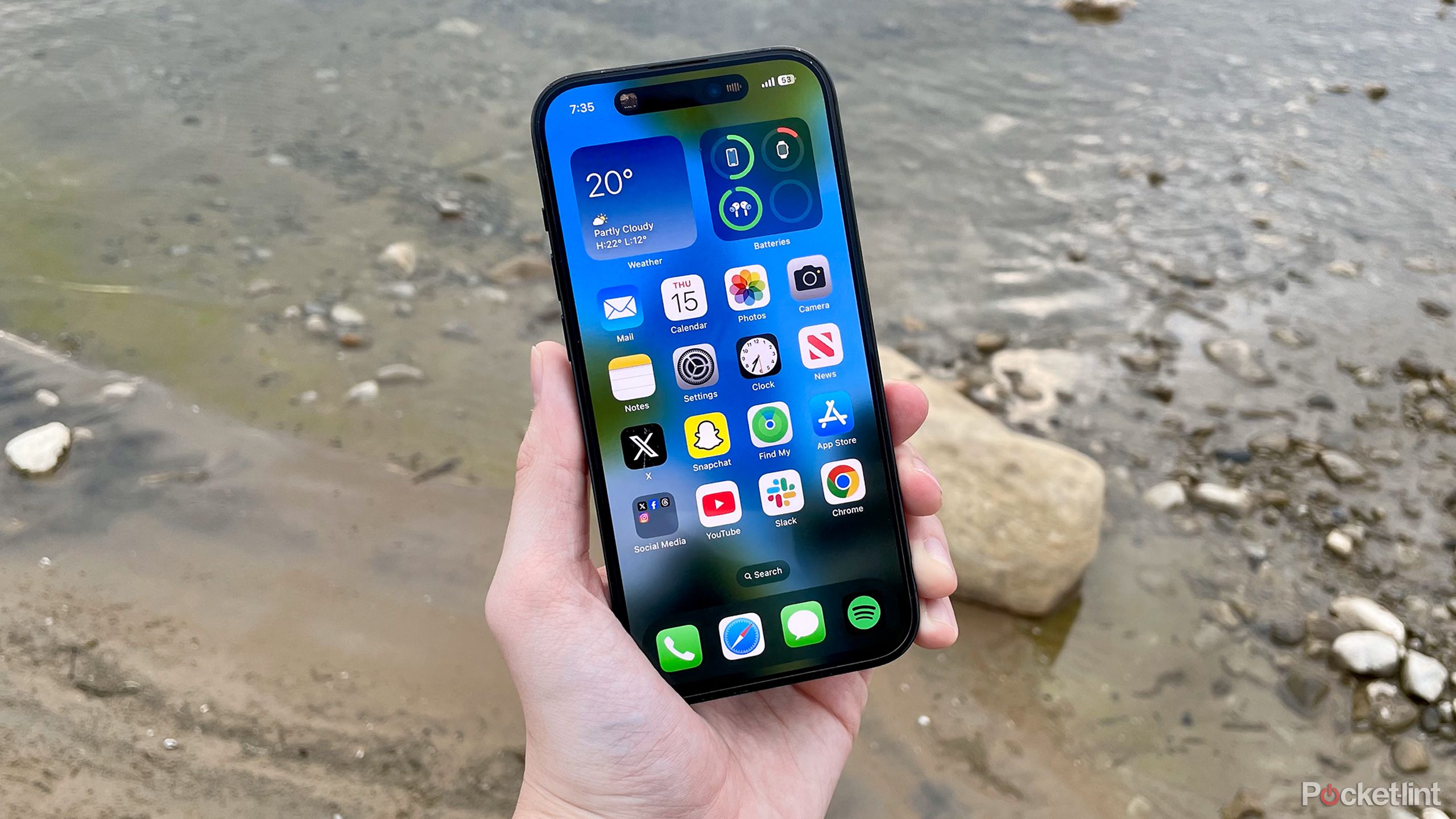iPhone 14 Pro near rocks and water.