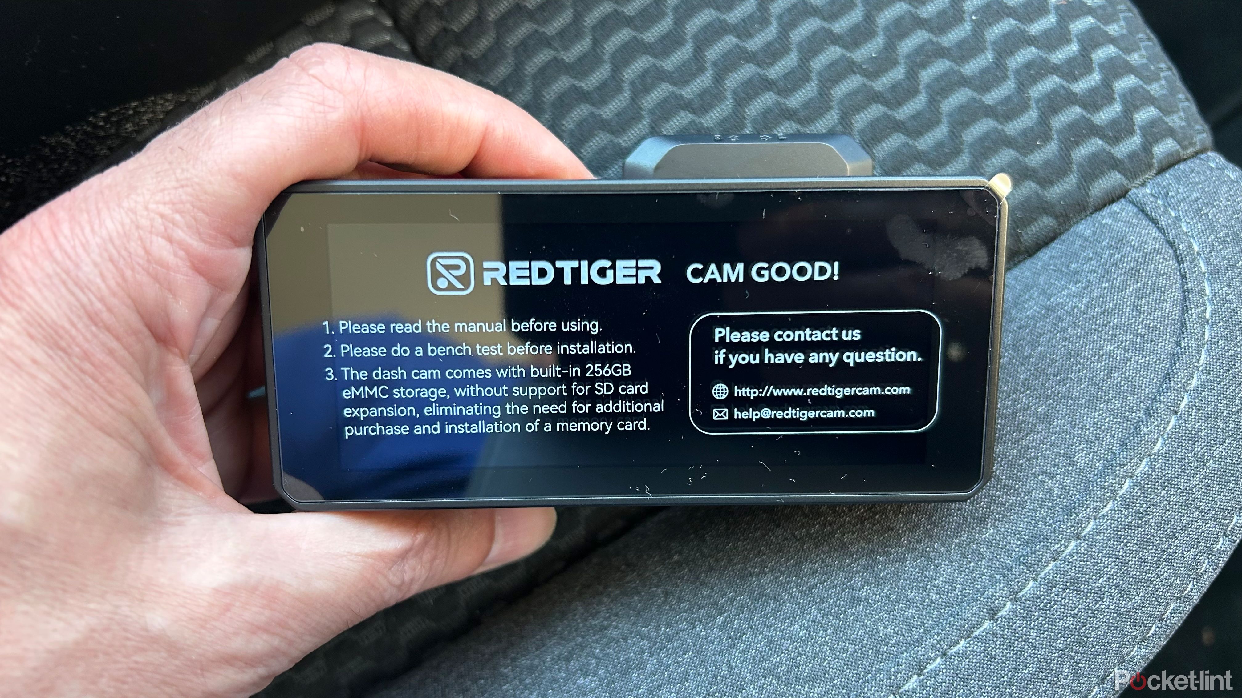 Redtiger F77 Dash Cam in hand on top of a car seat. 