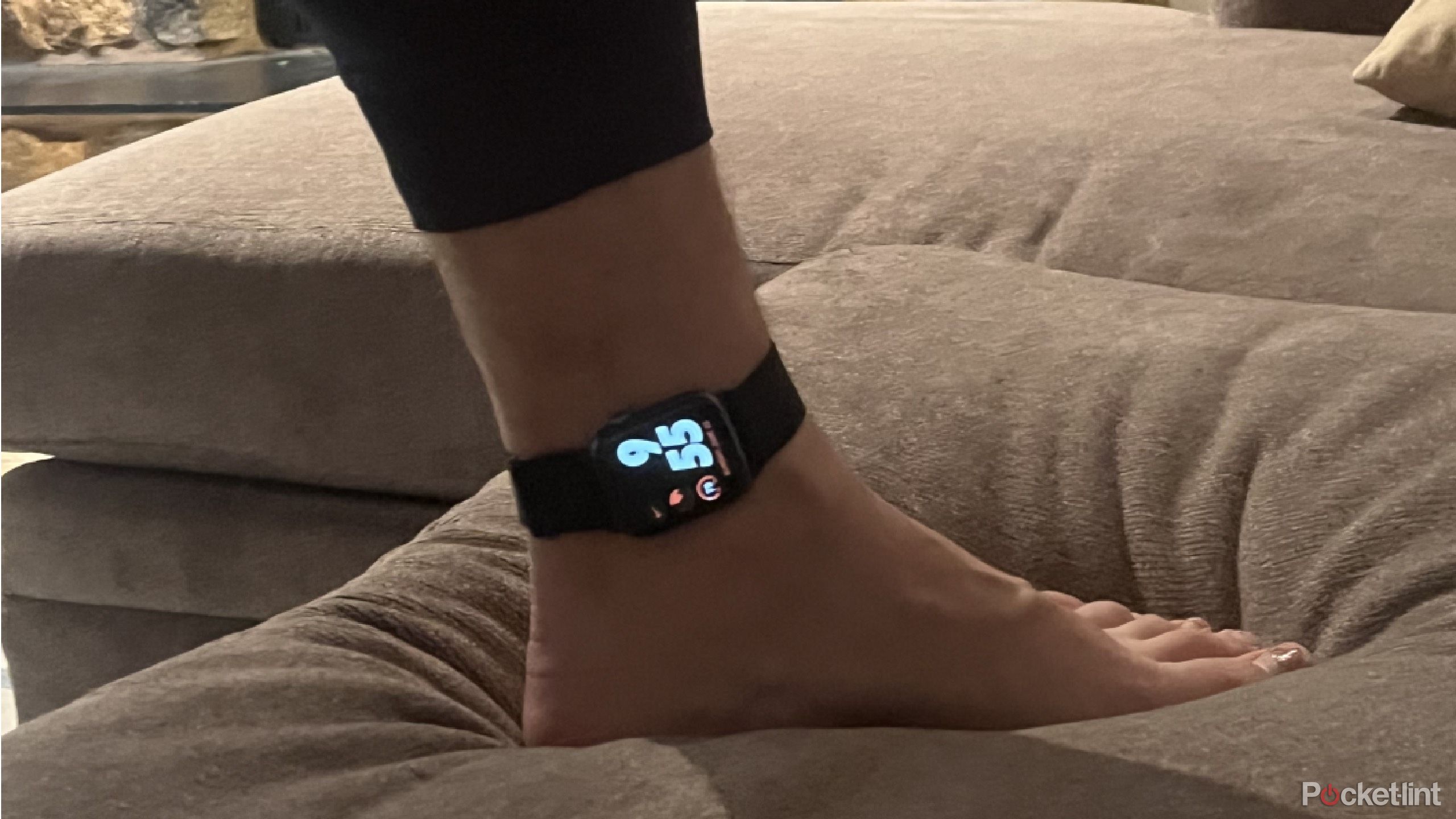 An Apple Watch on an ankle on a couch
