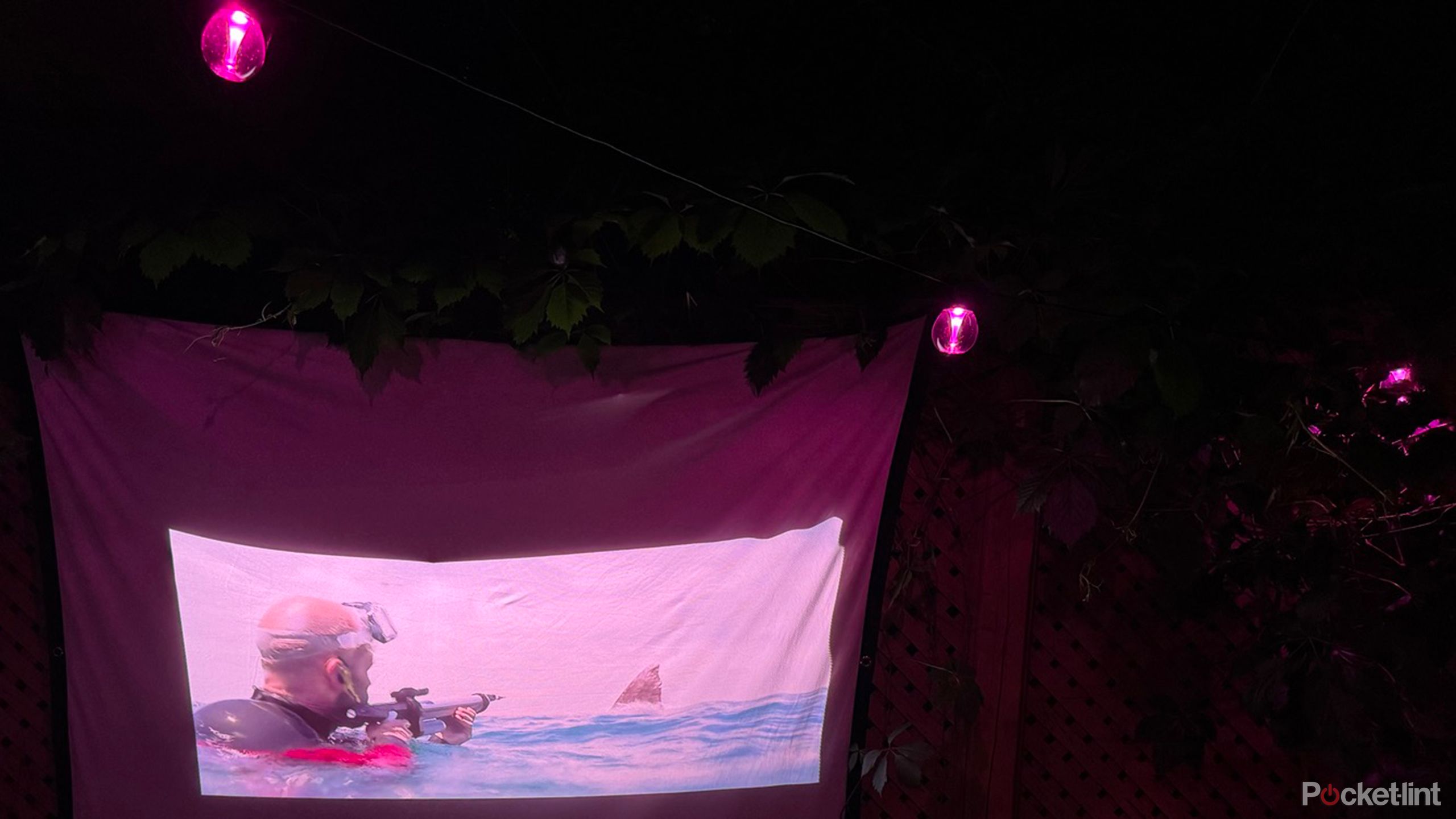 Govee Outdoor strings lights hanging over an outdoor projector screen playing a movie