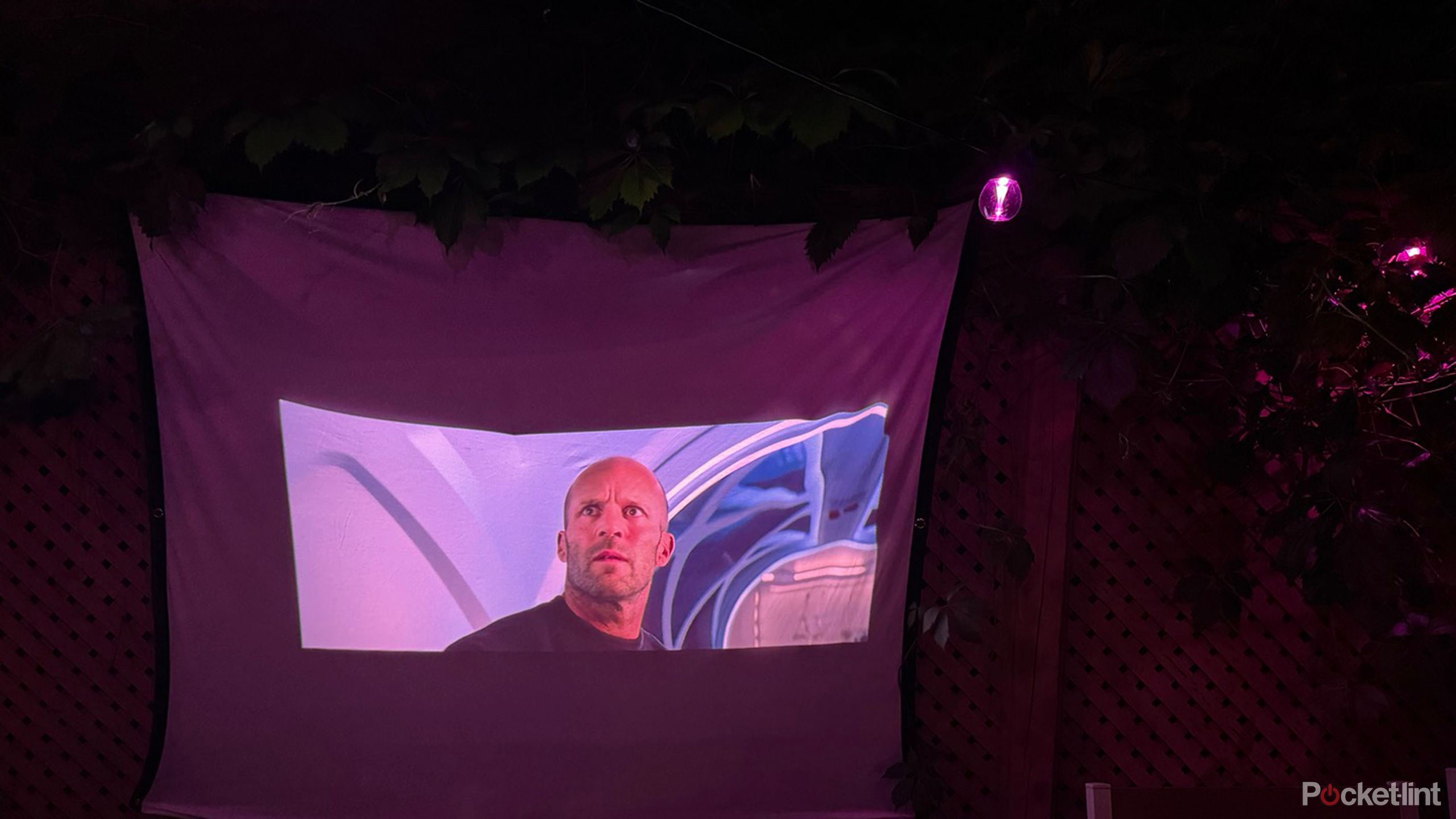 Govee Outdoor strings lights hanging over an outdoor projector screen playing a movie