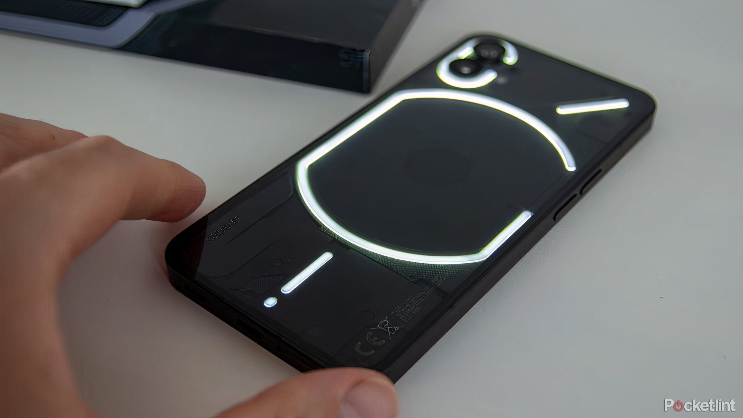 A black Nothing Phone (1) with its back Glyph Interface lit up.